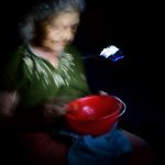 Mi abuela comiendo sopa en plena oscuridad iluminada por la luz de un celular